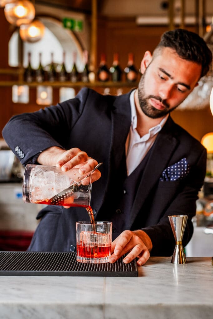Bartender is pouring cocktail.