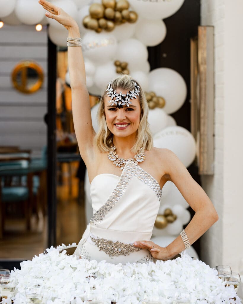 Smiling blonde woman in elegant white costume.